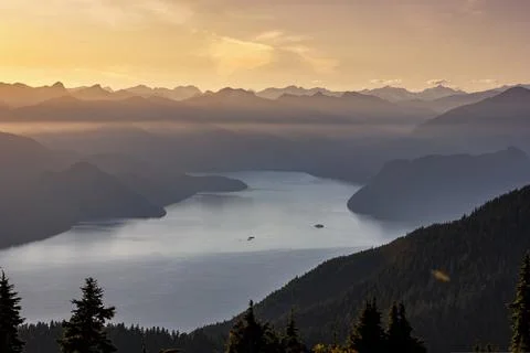 Dramatic sunset over a serene lake with mountains in the distance showcasin.. Stock Photos
