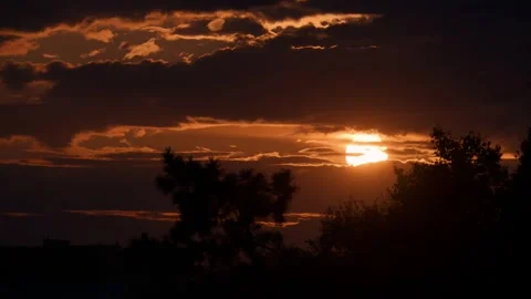 Dramatic sunset over silhouetted trees with vibrant orange clouds creating .. Stock Footage 339258059