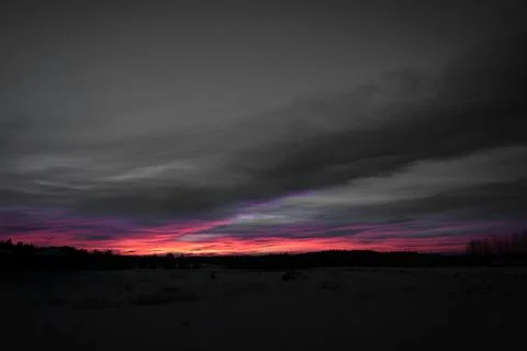 Dramatic Sunset over a Snowy Landscape with Forest Silhouettes Stock-Fotos