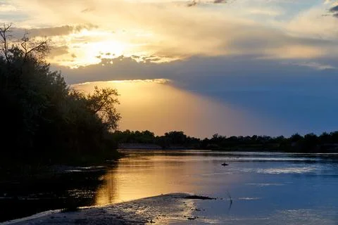 Dramatic sunset over a steppe river with a calm current Stock Photos