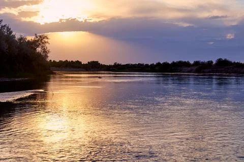 Dramatic sunset over a steppe river with a calm current Stock Photos