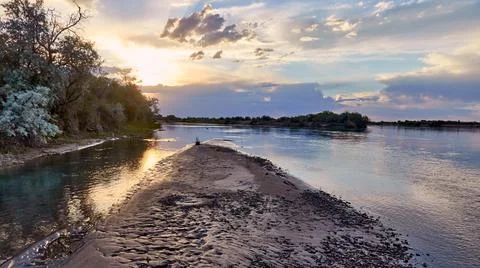 Dramatic sunset over a steppe river with a calm current Stock Photos