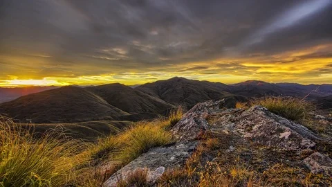 Dramatic Sunset over tussock and rock outcrop covered mountains Stock Footage 73844250