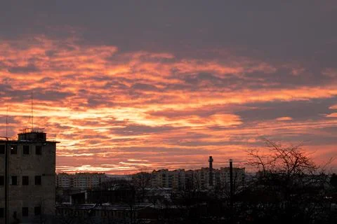 Dramatic sunset over an urban skyline with orange clouds and silhouettes of Stock-Fotos