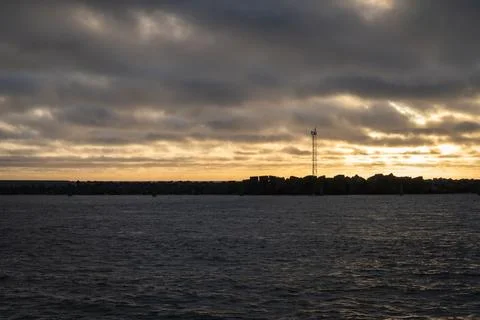 Dramatic sunset over water with silhouetted landscape and tower Stock Photos