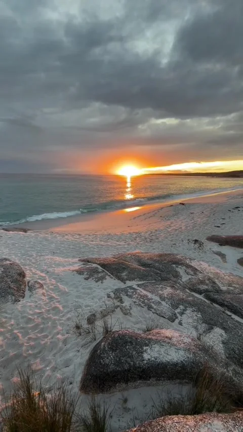 Dramatic sunset over white sand beach with granite rocks Stockbeeldmateriaal 334084895