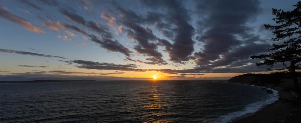 A dramatic sunset panorama over the ocean with colorful skies Stock Photos