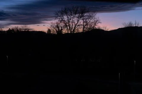 Dramatic sunset with pink blue clouds over bar trees and hills in wintertime Stock Photos