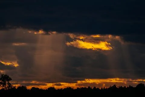 Dramatic sunset with rays of sunlight breaking through dark clouds over a s.. Stock Photos