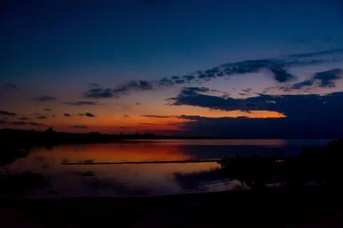 Dramatic sunset reflecting on calm lake waters at dusk Stock Photos