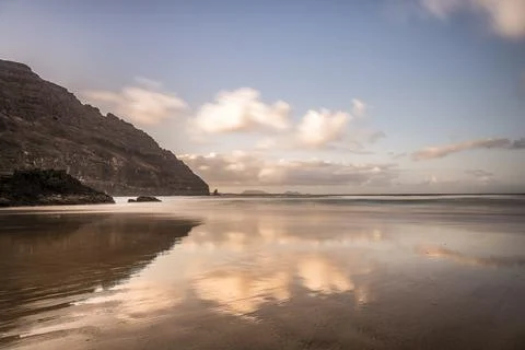 Dramatic Sunset Reflection on a Wet Beach with Volcanic Cliffs. Travel Concep Foto stock