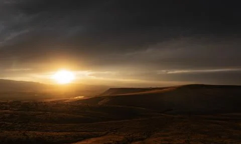 Dramatic sunset scene over hilly terrain with clouds Stock Photos