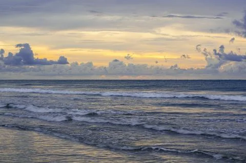 Dramatic sunset seascape with dark cloud bands over glowing horizon and rol.. Stock Photos