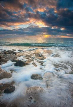 Dramatic Sunset Seascape with Pebbles and Foamy Waves Stock-Fotos