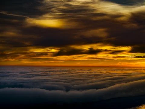 Dramatic sunset sky ablaze with fiery orange and dark clouds over a sea of fo Fotos de archivo