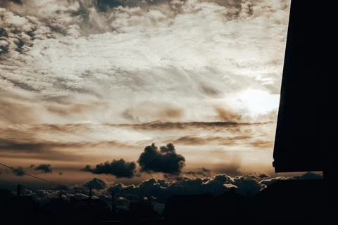 Dramatic sunset sky above suburban rooftops with layered clouds Stock Photos