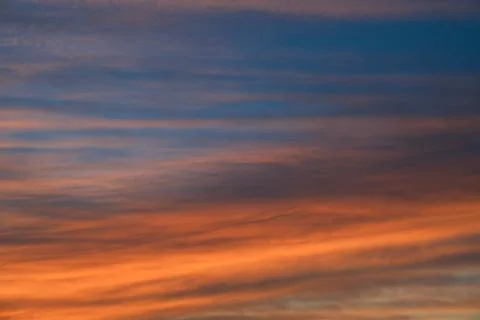 Dramatic sunset sky background with fiery clouds, yellow, orange and pink col Stock Photos