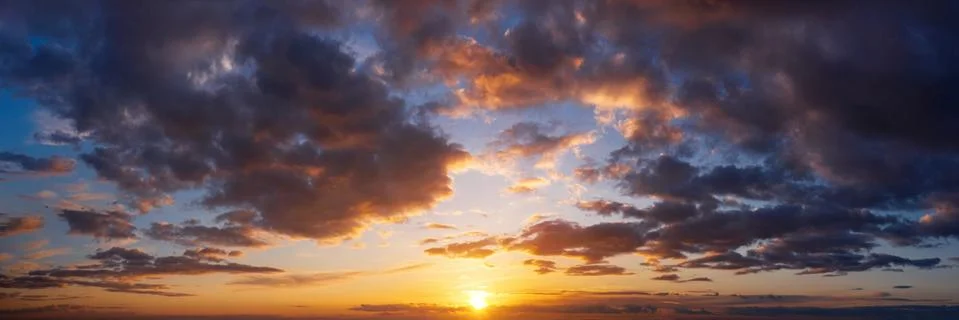 Dramatic sunset sky with clouds. Natural panorama of sky with setting sun. Stock Photos