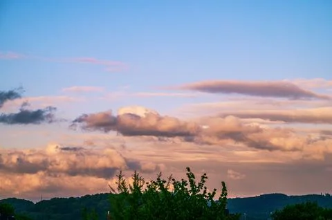 Dramatic sunset sky with colorful clouds over a distant green landscape Стоковые фото