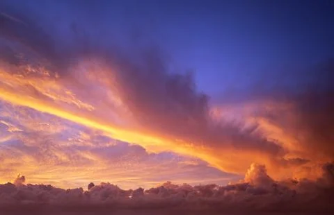 Dramatic sunset sky covered with colorful yellow clouds. Panoramic skyscape Photos
