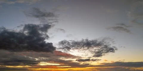 Dramatic sunset sky covered with colorful yellow clouds. Panoramic skyscape Stock Photos