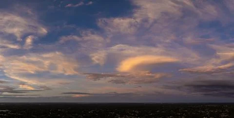 Dramatic sunset sky covered with colorful yellow clouds over dark ground. P.. Stock Photos