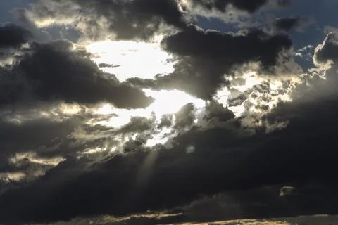 Dramatic sunset sky with dark clouds and sunbeams. Stock Photos