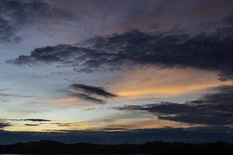 Dramatic sunset sky with dark clouds casting shadows and vibrant hues, perfec Stock Photos