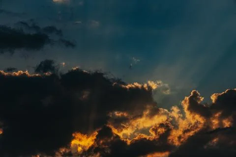 Dramatic sunset sky with dark clouds illuminated by golden sunlight rays br.. Stock Photos