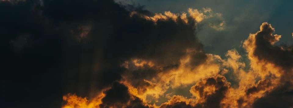 Dramatic sunset sky with dark clouds illuminated by golden sunlight, showca.. Stock Photos