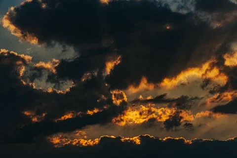 Dramatic sunset sky with dark clouds illuminated by golden sunlight, creati.. Stock Photos