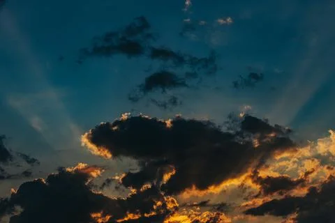 Dramatic sunset sky with dark clouds illuminated by golden light and rays o.. Stock Photos