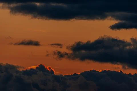Dramatic sunset sky with dark clouds and vibrant orange hues illuminating t.. Stock Photos