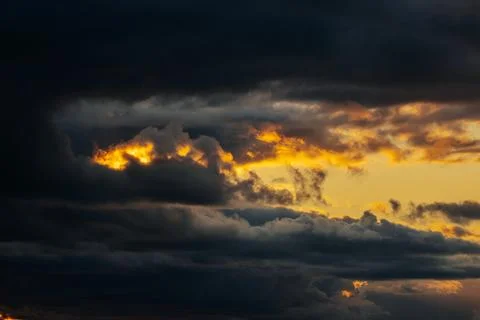 Dramatic sunset sky with dark storm clouds and vibrant orange and yellow hu.. Stock Photos