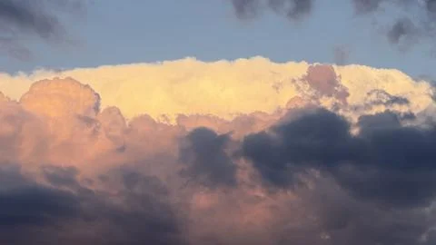 Dramatic sunset sky featuring a bright golden-illuminated cloud edge emerging Stock Photos