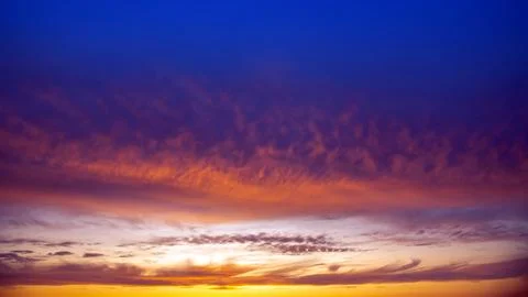 Dramatic sunset sky featuring golden, fiery clouds against a deepening blue.. Stock Photos