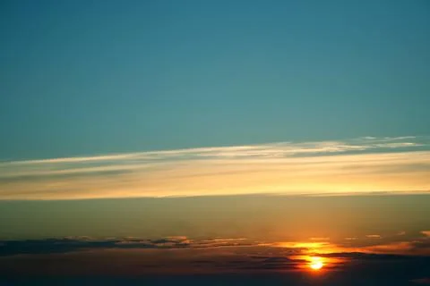 Dramatic sunset sky featuring golden, fiery clouds against a deepening blue.. Stock Photos