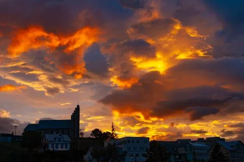 Dramatic sunset sky glowing above a large town church Stock Photos