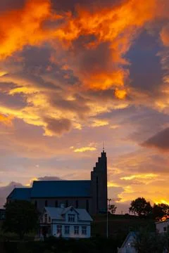 Dramatic sunset sky glowing above a large town church Stock Photos