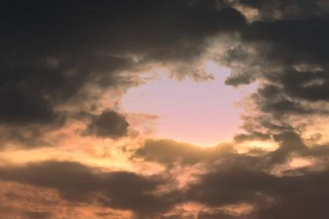 Dramatic sunset sky with glowing clouds and a soft pink opening Stock Photos
