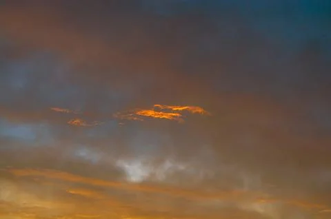 Dramatic sunset sky with glowing orange clouds and deep blue hues creating .. Stock Photos