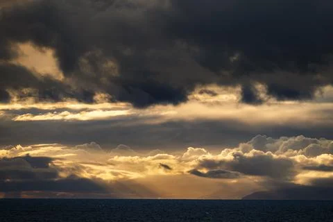 Dramatic sunset sky with golden light breaking through dark storm clouds ov.. Fotos de archivo