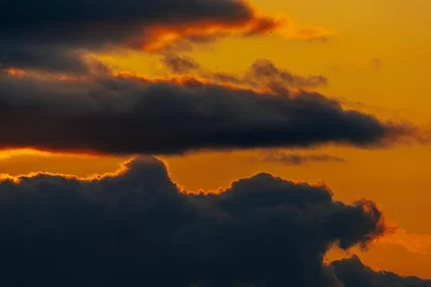 Dramatic sunset sky with layered clouds illuminated by warm orange and yell.. Stock Photos