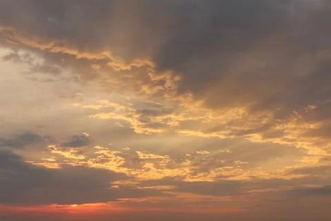 Dramatic sunset sky with orange colored clouds and last rays of the sun, colo Stock Photos