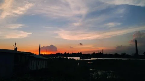 Dramatic sunset sky with orange horizon reflections over quiet river beside.. Stockfoto's
