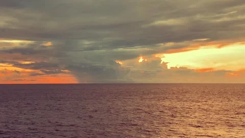Dramatic sunset sky over a calm ocean with vibrant colors reflecting on the.. 動画素材 338281464