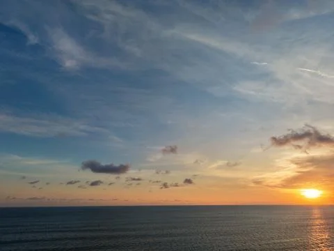Dramatic sunset sky over calm ocean water with golden sunlight Stock Photos