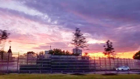 Dramatic sunset sky over a cityscape with car driving. Blurred motion Stock Photos
