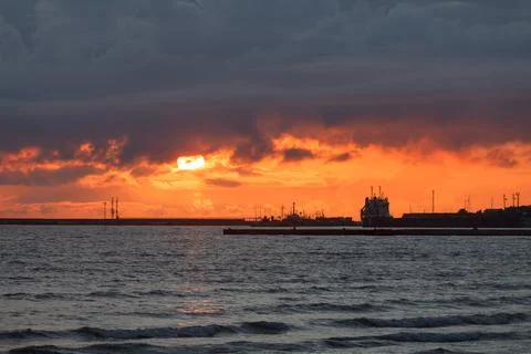 Dramatic sunset sky over the sea and the pier. Stock Photos