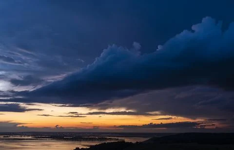 Dramatic sunset sky over Volga river, blue clouds hang over water Stock Photos